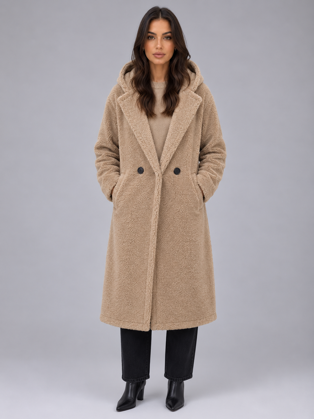 Woman wearing beige oversized hooded teddy coat with double-breasted buttons over cream sweater, styled with black jeans and black boots