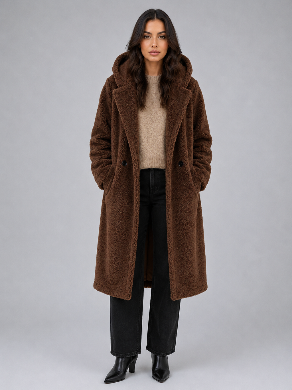 Woman wearing brown oversized hooded teddy coat over beige sweater and black jeans with black boots