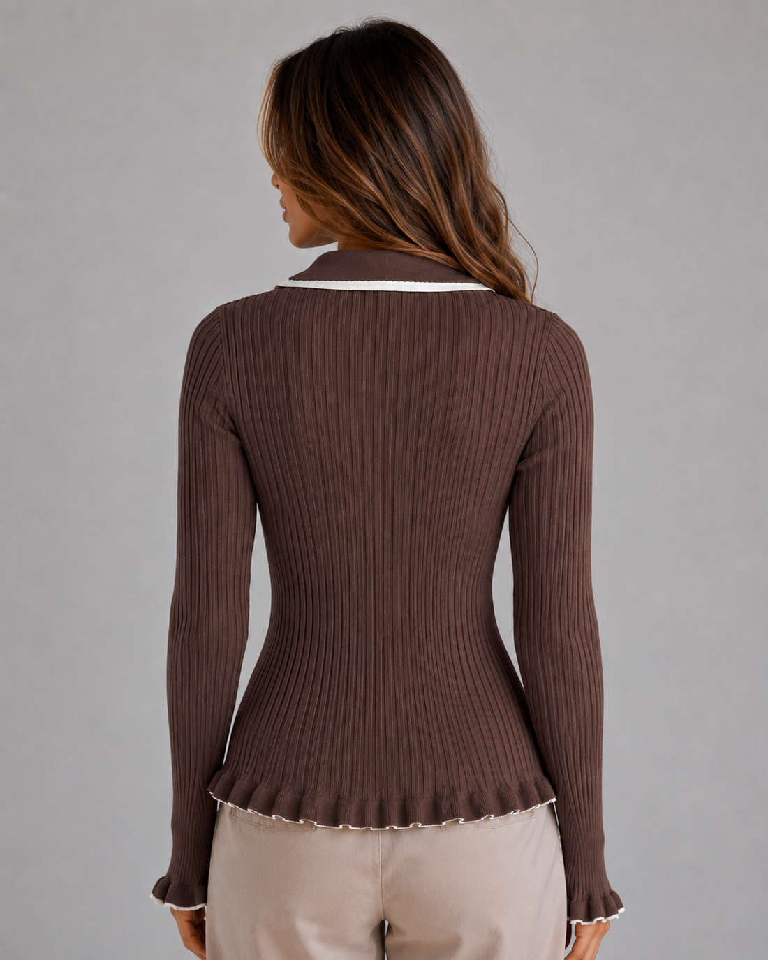 Woman wearing brown ribbed knit long sleeve polo top with white collar trim and cream pants, back view