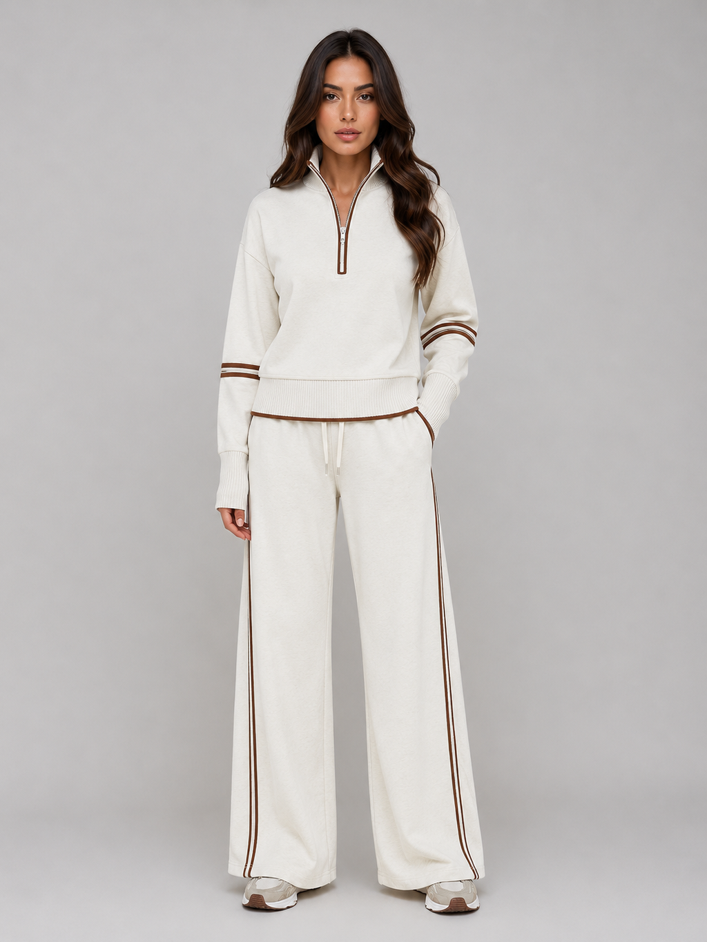 Woman wearing cream relaxed wide leg tracksuit with brown stripe trim, half zip sweatshirt and matching lounge pants