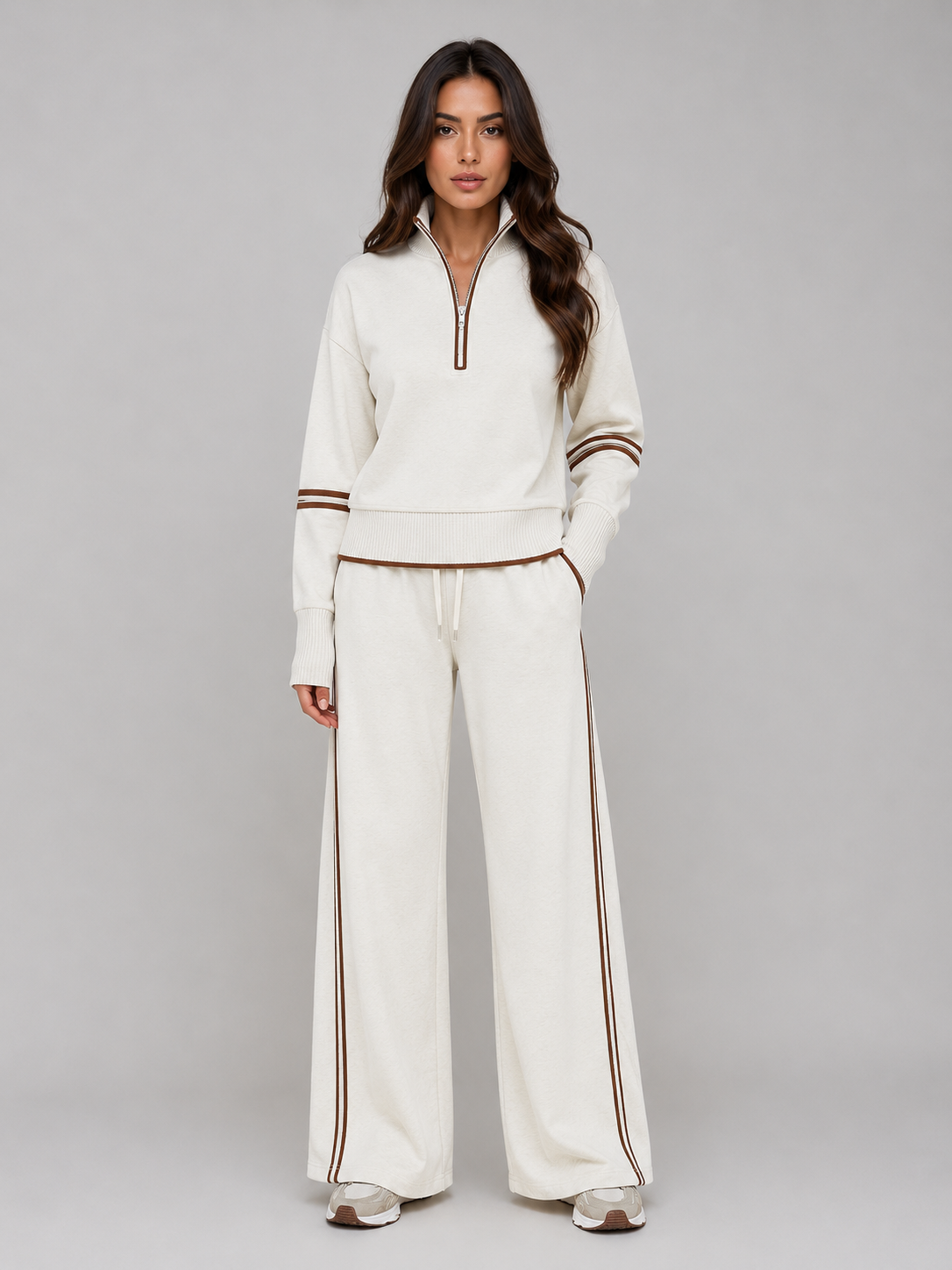 Woman wearing cream relaxed wide leg tracksuit with brown stripe trim, half zip sweatshirt and matching lounge pants