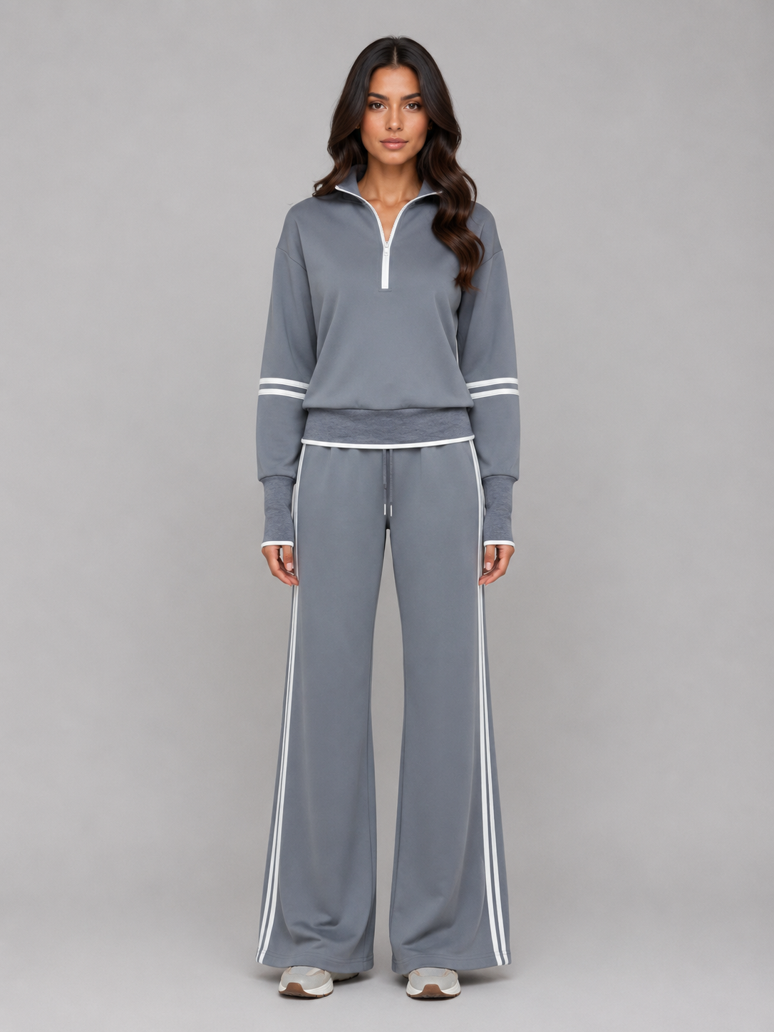 Woman wearing grey half-zip crop sweatshirt and matching wide-leg sweatpants with white stripe trim