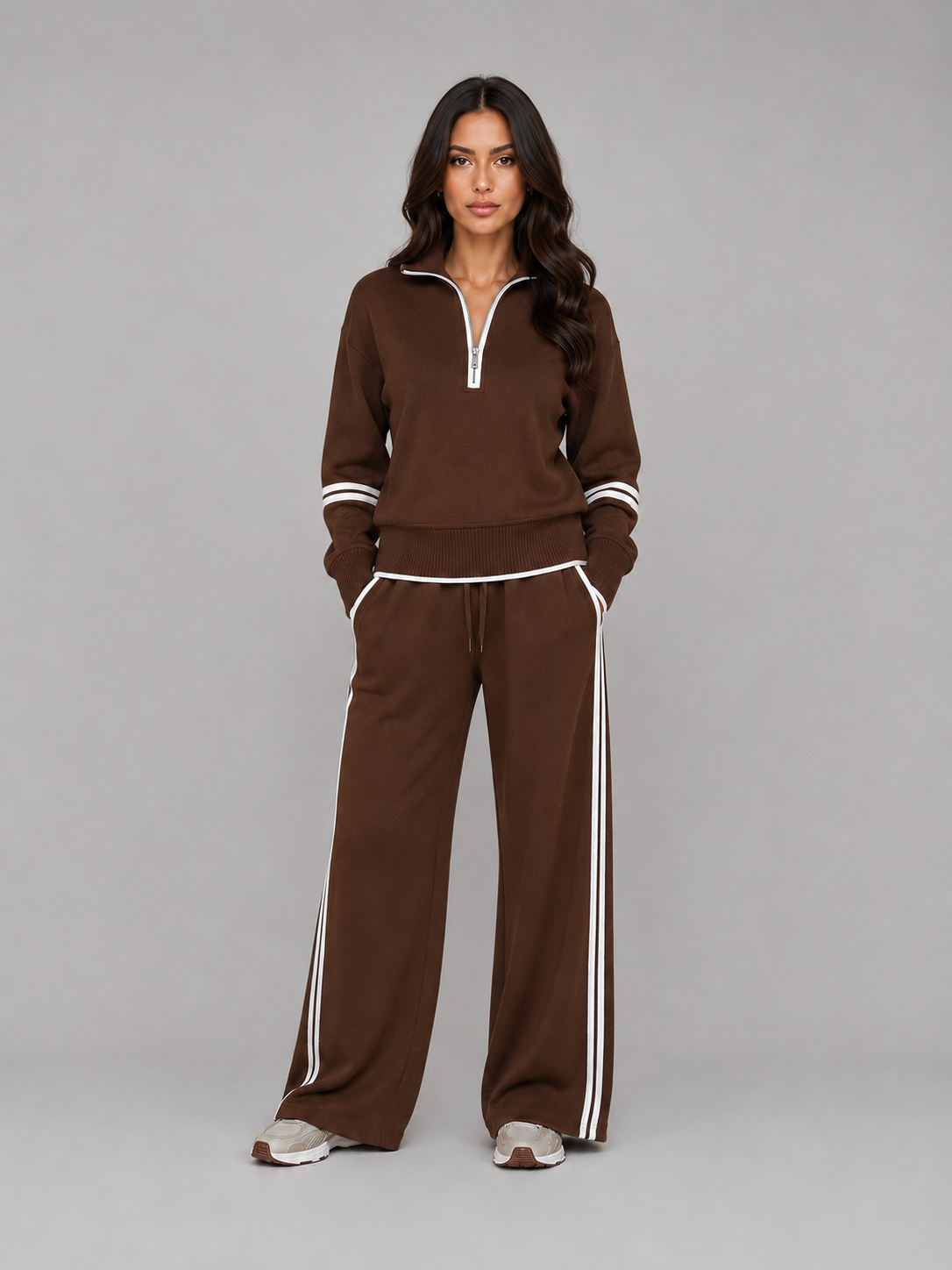Woman wearing brown relaxed wide leg tracksuit with white stripes, half zip top, and matching lounge pants