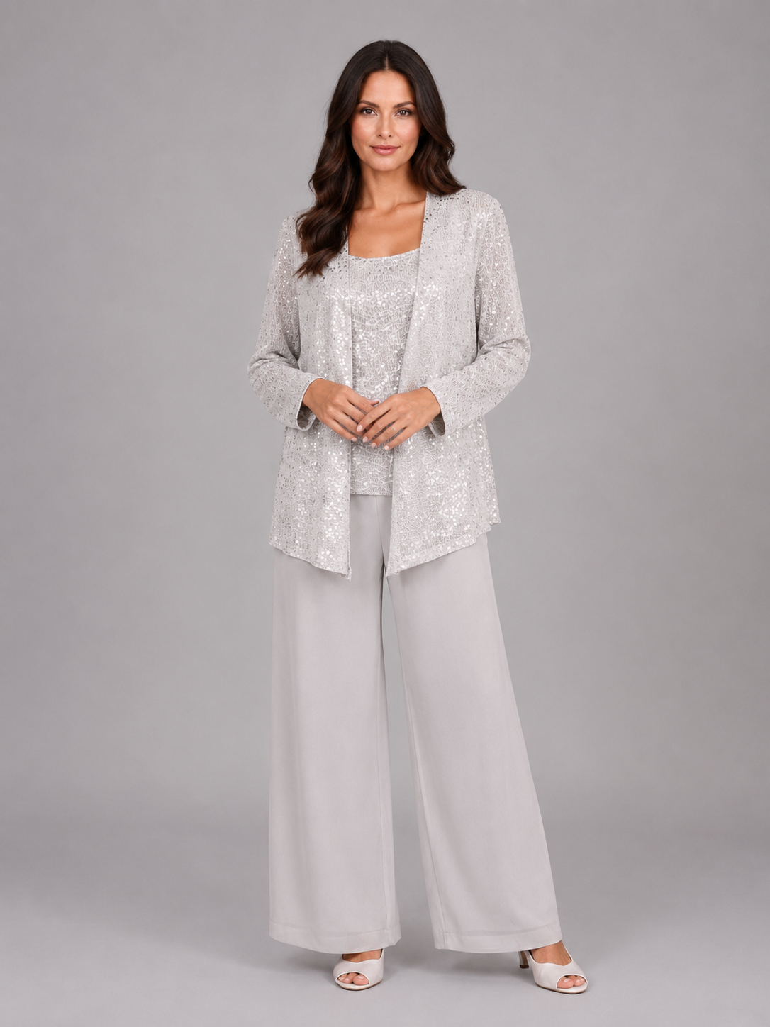 Woman wearing silver sequin cardigan with matching tank top and white wide-leg trousers, styled with white sandals