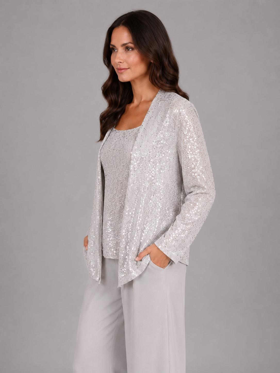 Woman wearing silver sequin cardigan with matching camisole and cream trousers, elegant three-piece occasion set