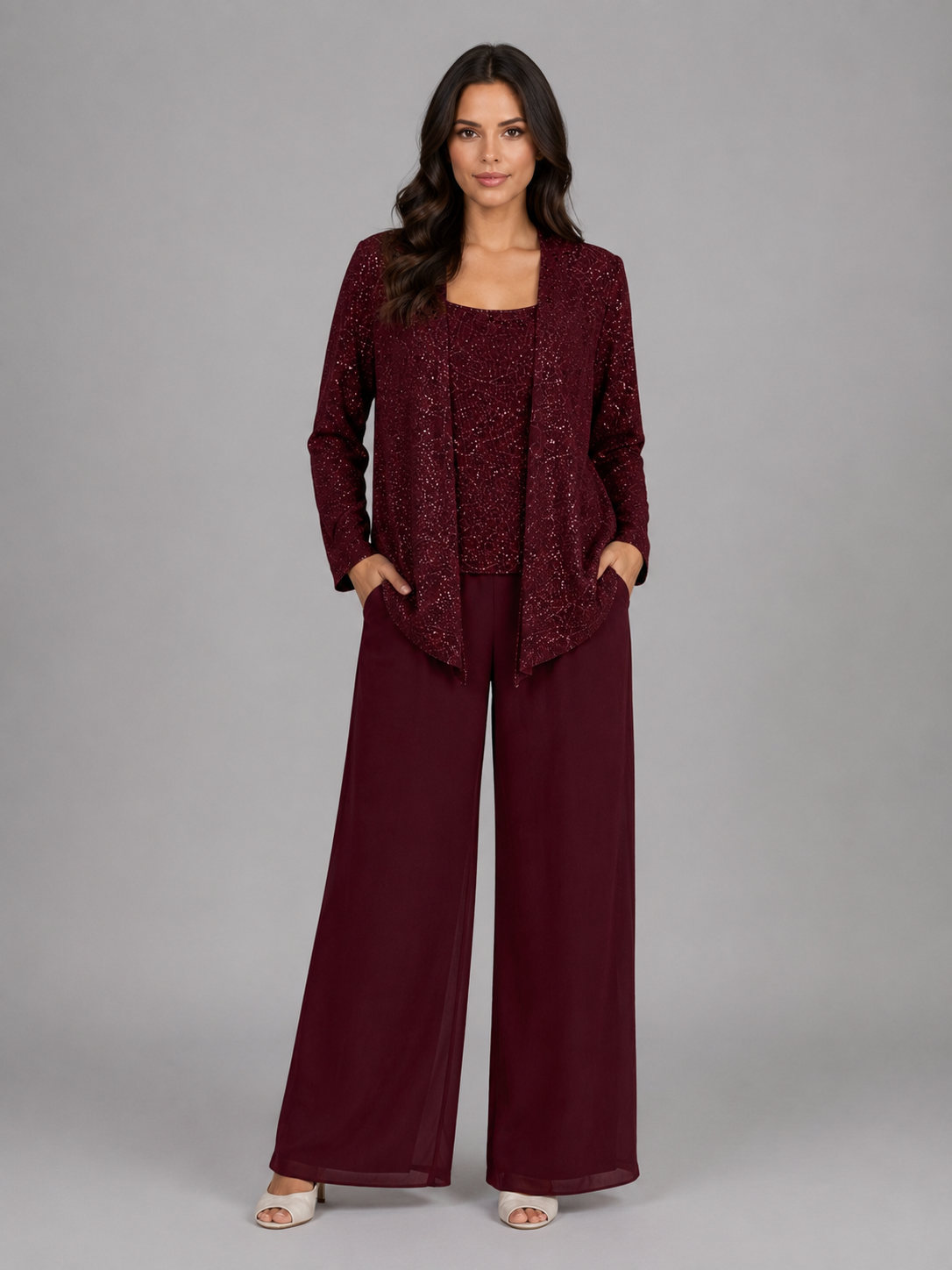 Woman wearing burgundy sequin cardigan with matching tank top and wide-leg trousers, styled with white sandals