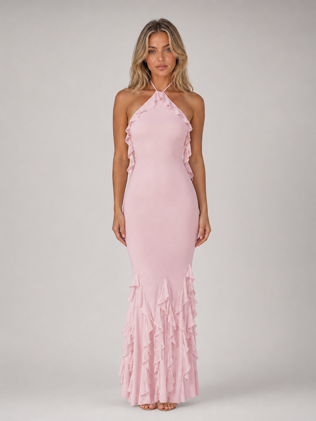 Woman wearing pink halterneck bodycon maxi dress with ruffle side detailing and cascading fishtail hem