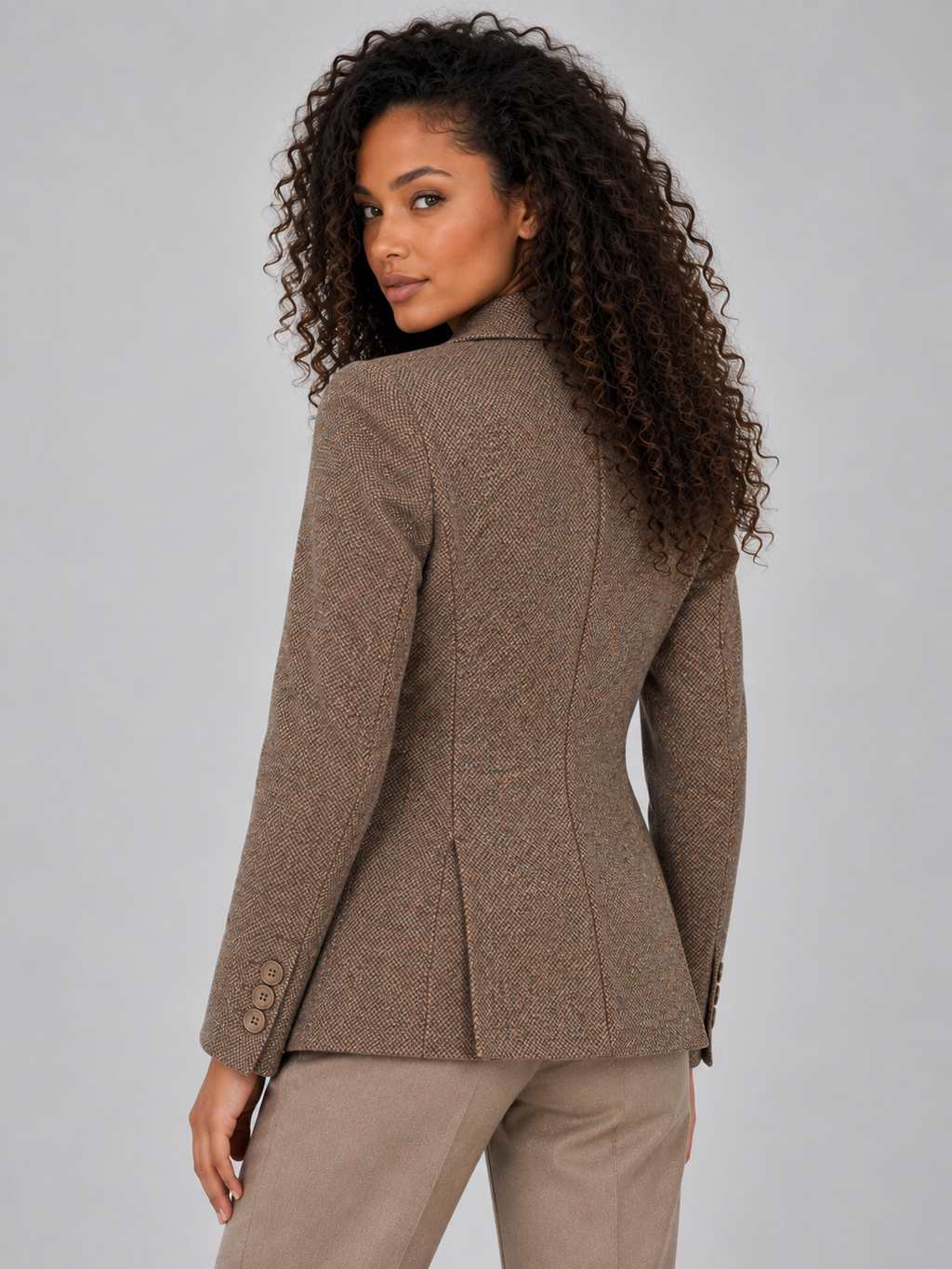 Woman wearing taupe wool blend tailored blazer with notch lapels and button cuffs, paired with matching trousers