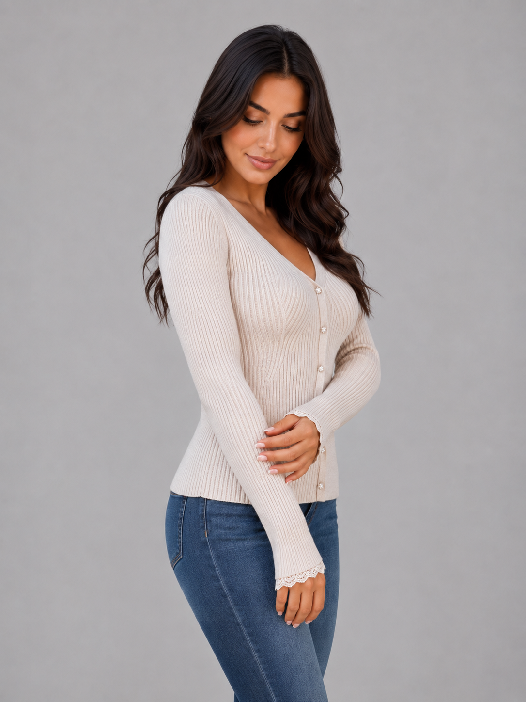 Woman wearing cream ribbed knit cardigan with white buttons and lace cuffs over blue jeans