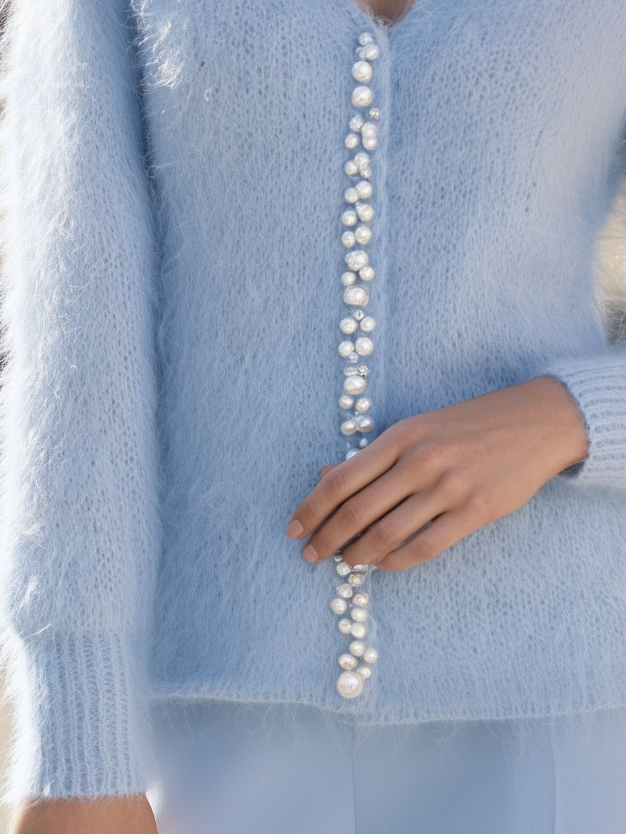 Light blue fuzzy cardigan with pearl button embellishment down center front, worn by woman with hand visible