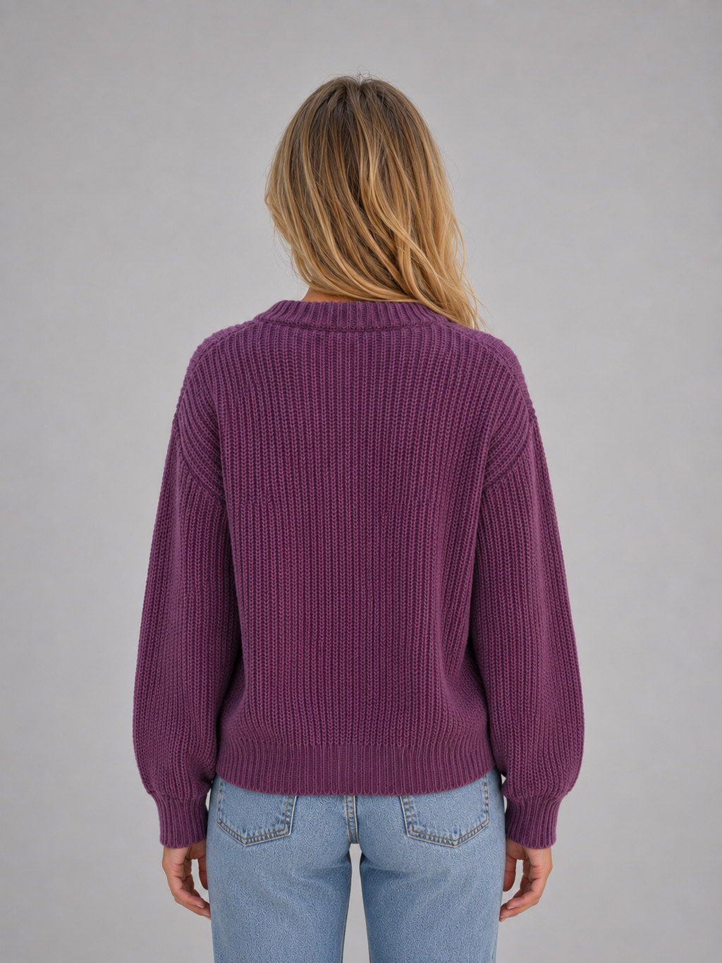 Woman wearing purple ribbed cardigan with button front and v-neck over light blue jeans, back view