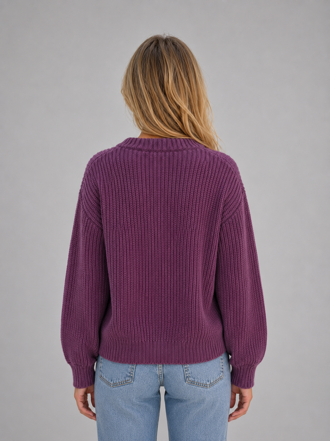 Woman wearing purple ribbed cardigan with button front and v-neck over light blue jeans, back view