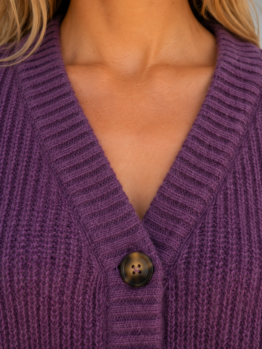 Woman wearing purple chunky knit ribbed cardigan with v-neckline and brown button closure