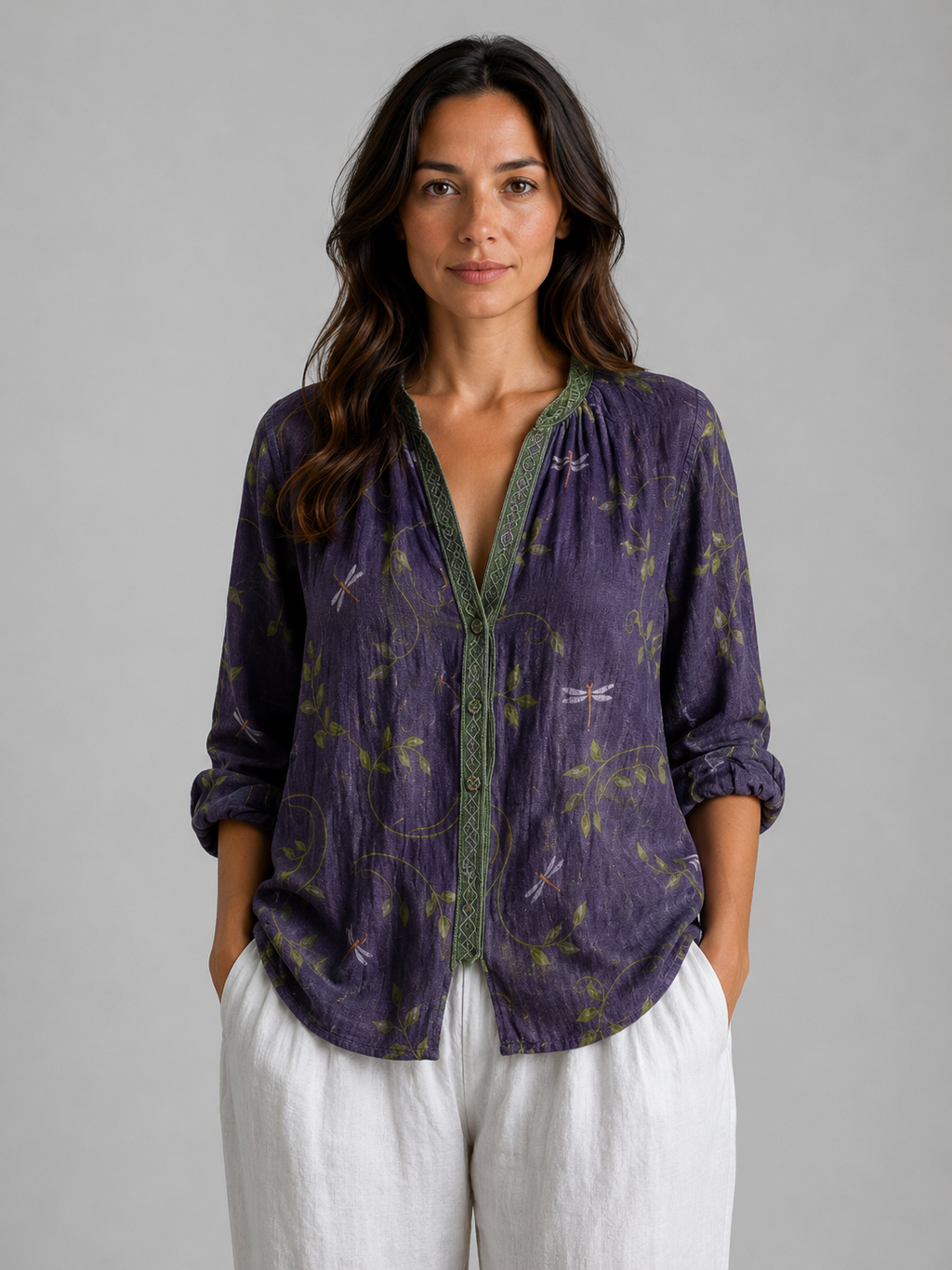 Woman wearing purple bohemian blouse with dragonfly print and green trim, paired with white linen pants