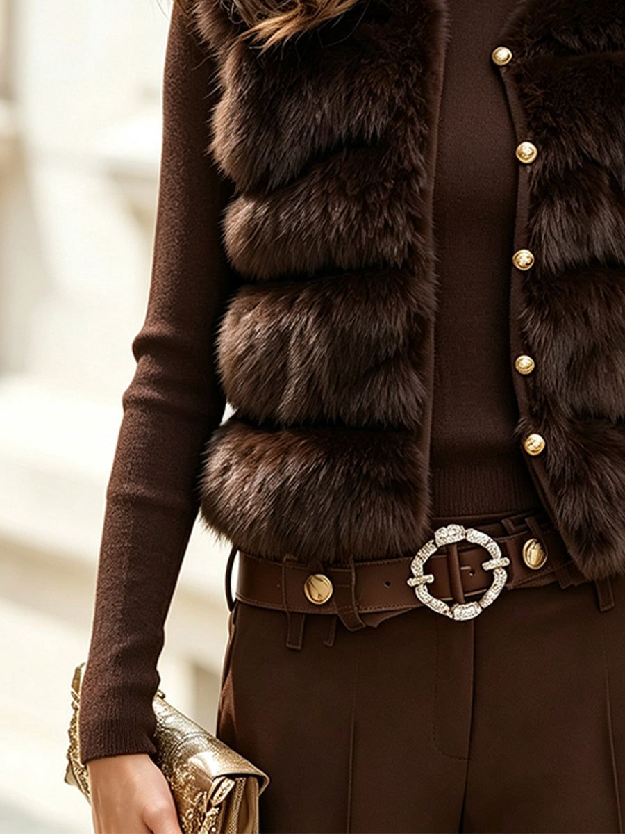 Brown faux fur vest with knit turtleneck sweater, decorative belt buckle, and gold clutch accessory