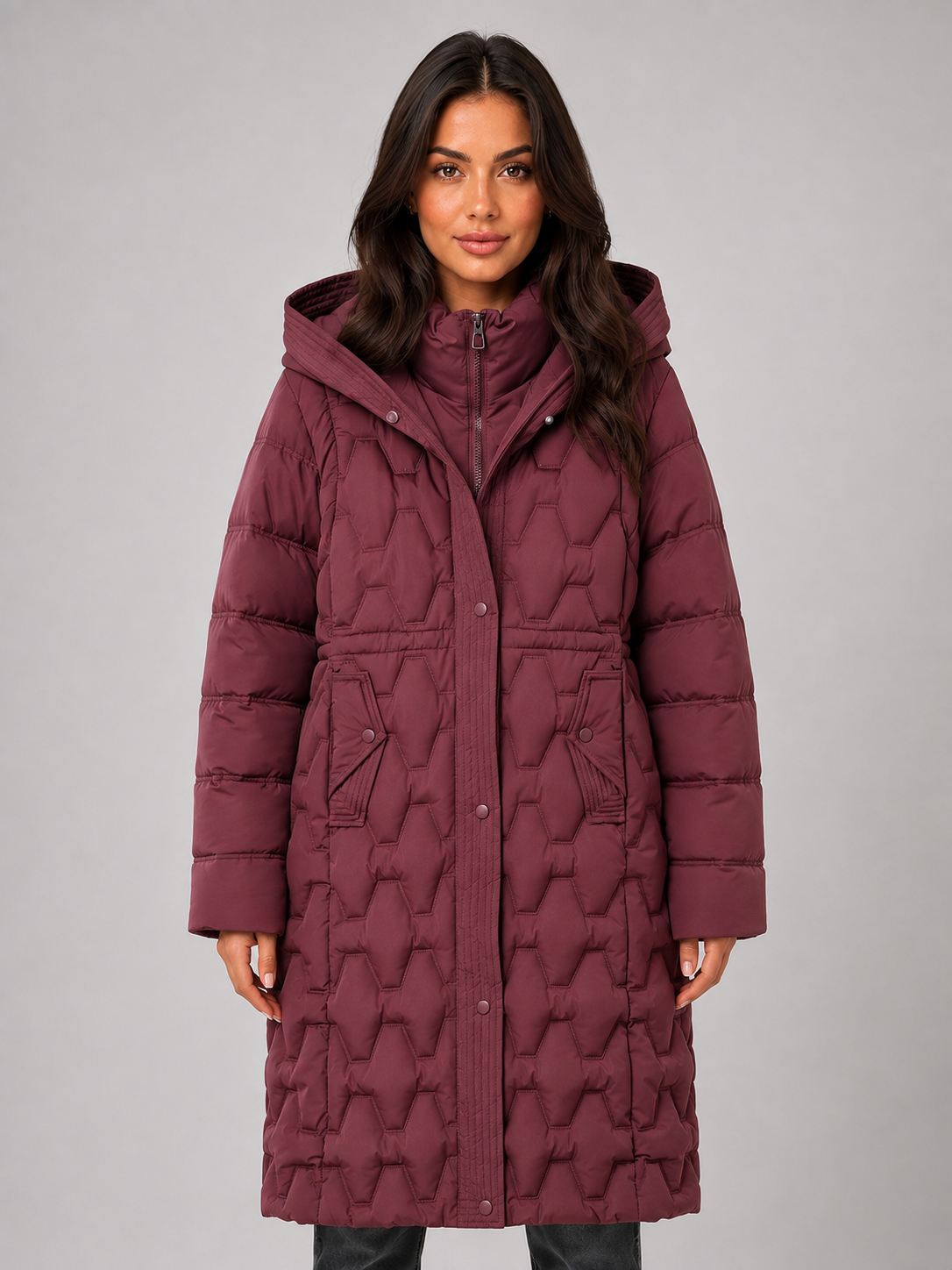 Woman wearing burgundy hooded quilted puffer coat with geometric pattern and snap button closure