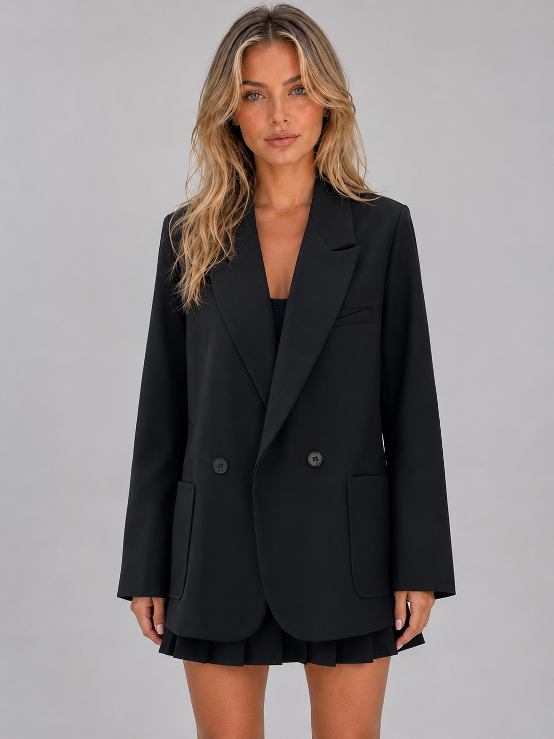 Woman wearing black oversized double breasted tailored blazer jacket with notch lapels and buttons over black skirt