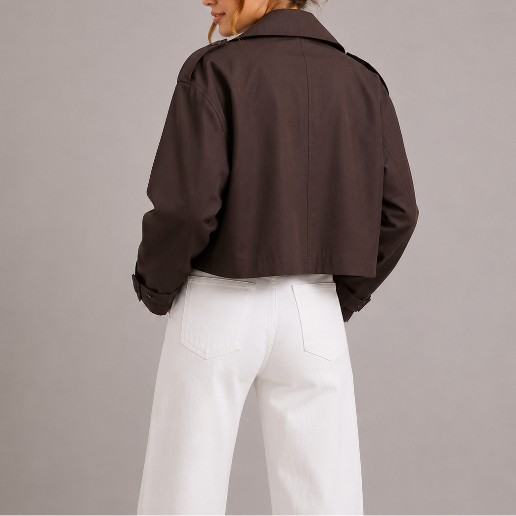 Woman wearing brown cropped trench jacket with white jeans, back view