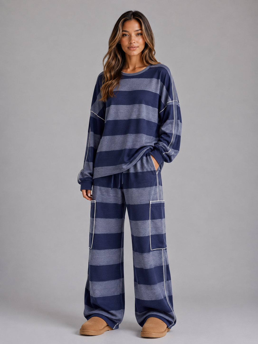 Woman wearing navy and grey striped oversized sweatshirt and matching wide leg lounge trousers with white piping detail