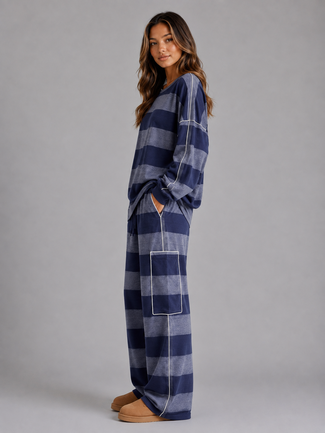 Woman wearing navy and gray striped oversized sweatshirt and matching wide leg lounge trousers with tan slippers