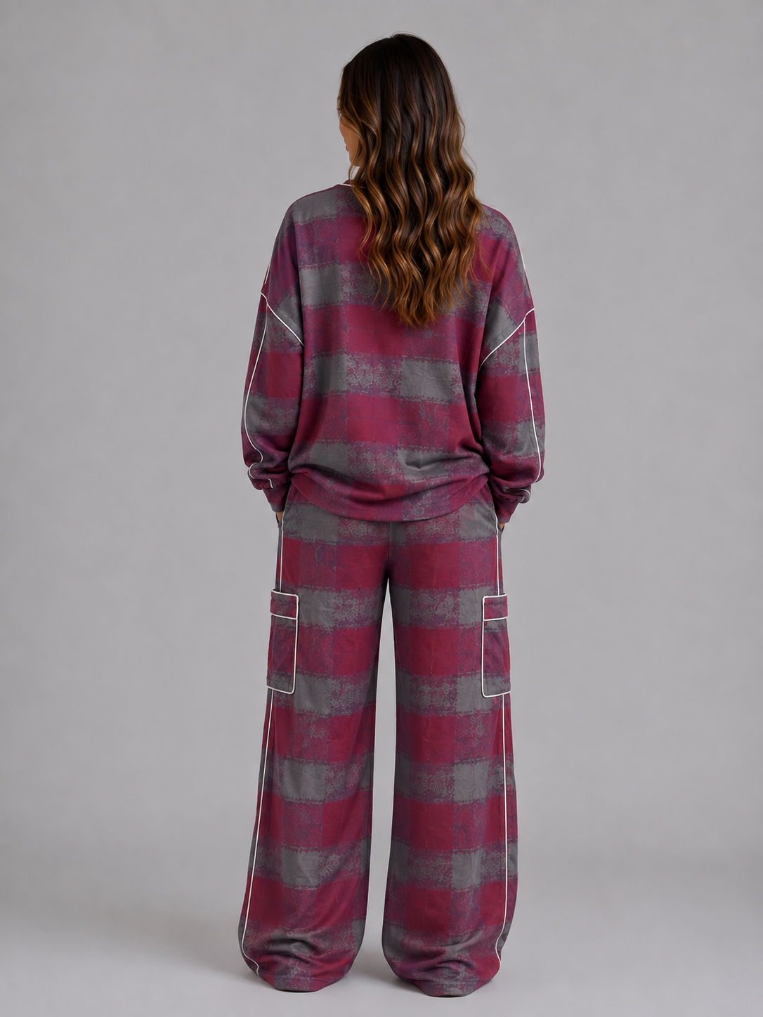 Woman wearing burgundy and gray striped oversized sweatshirt and matching wide leg cargo lounge trousers with white piping, shown from behind