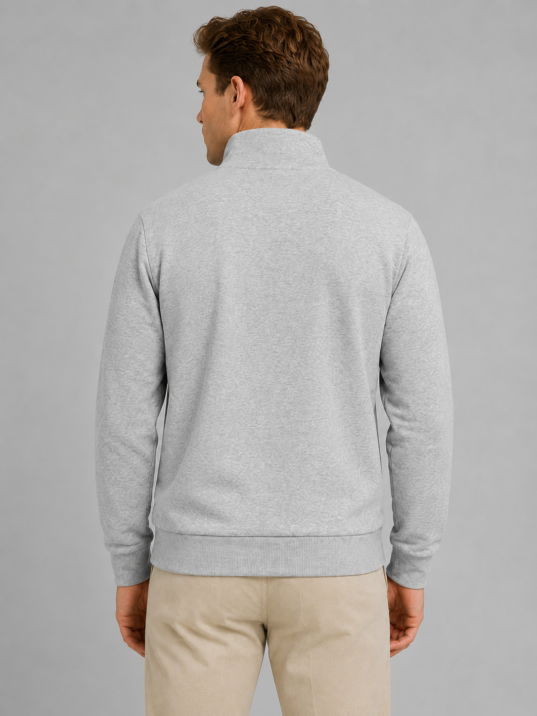 Man wearing light gray half-zip pullover sweatshirt with high neck and beige pants, back view against gray background