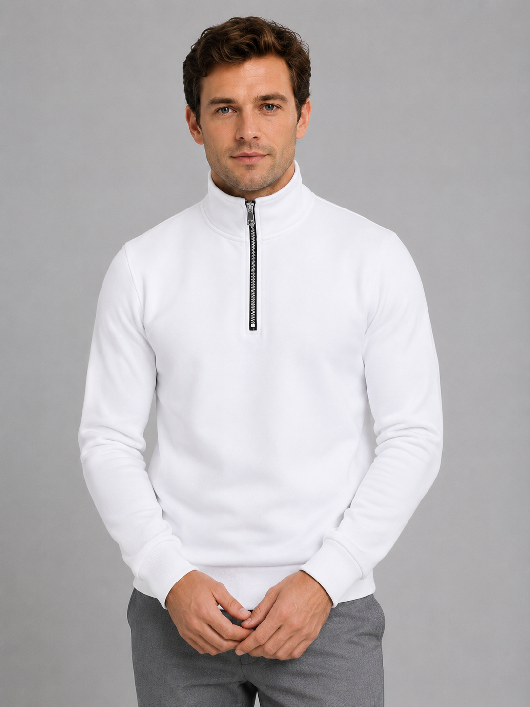 Man wearing white high neck half-zip pullover sweatshirt with gray pants, front view on gray background