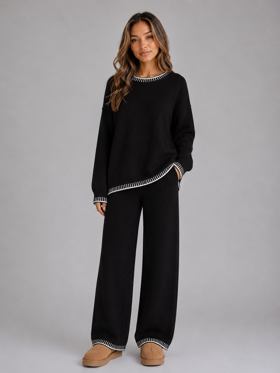 Woman wearing black knit sweater and wide leg trousers with white stripe trim, paired with tan platform slippers