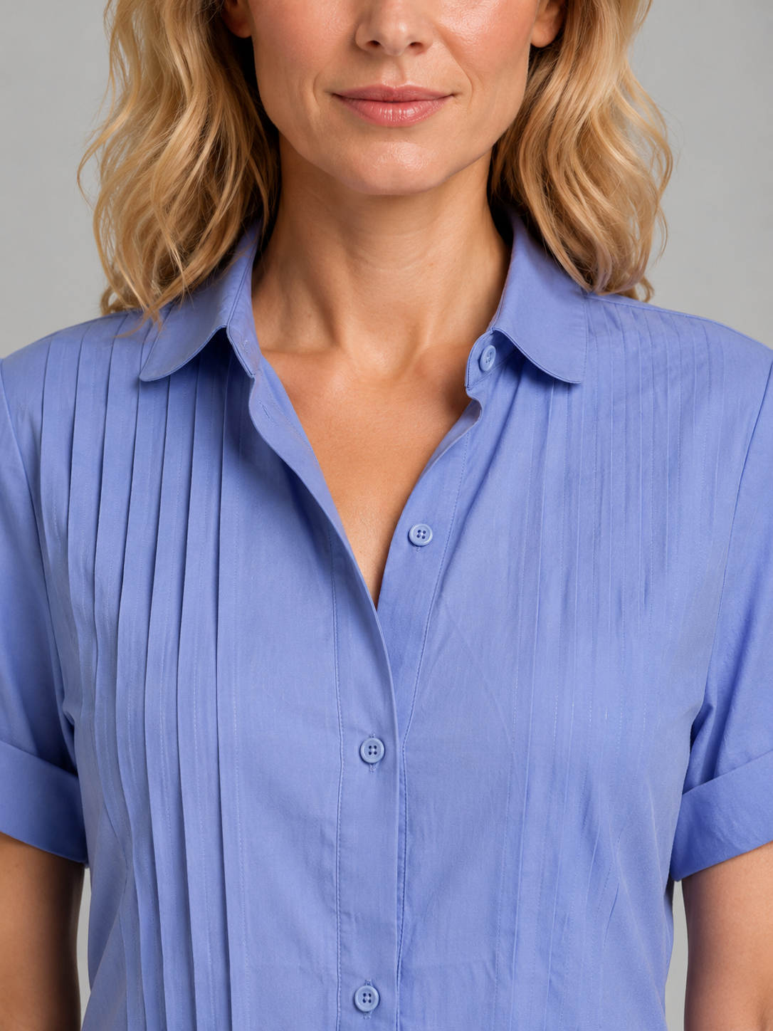 Woman wearing a light blue relaxed pleated shirt dress with short sleeves, button front, and collar