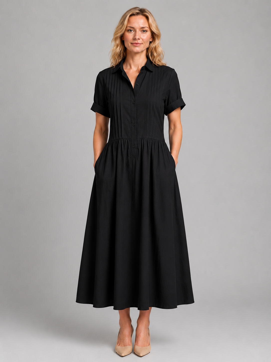 Woman wearing black short-sleeve button-down maxi dress with pleated front and pockets, paired with beige heels