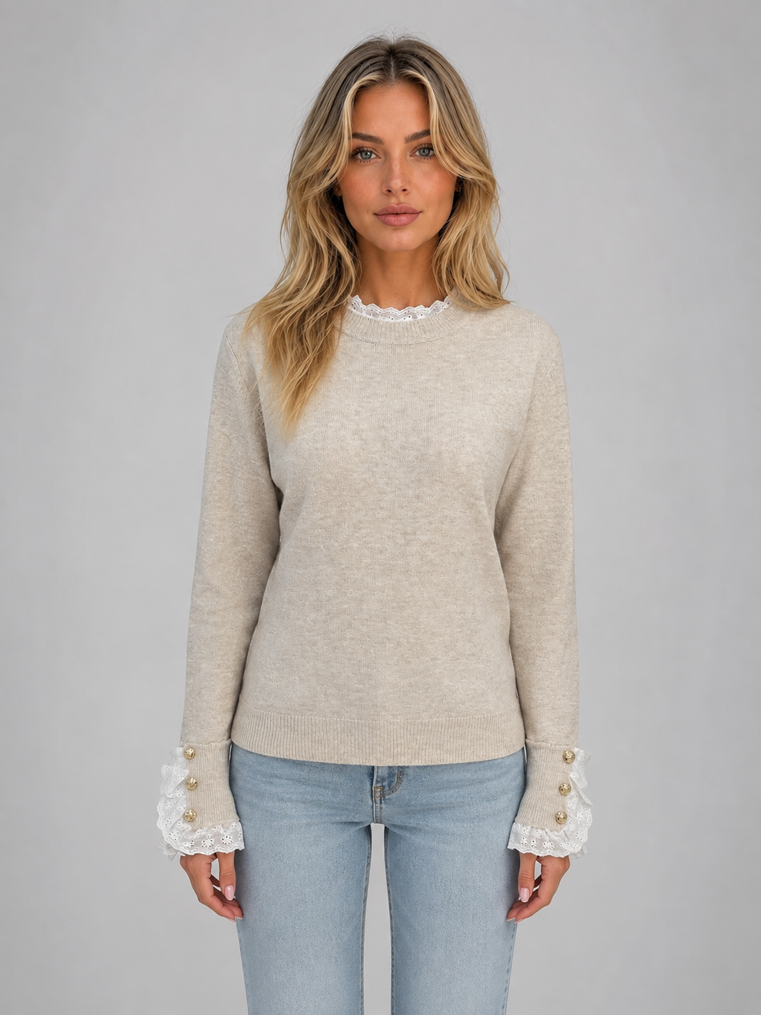 Woman wearing beige crew neck long sleeve knitted jumper with white lace trim and gold button cuffs, paired with light blue jeans