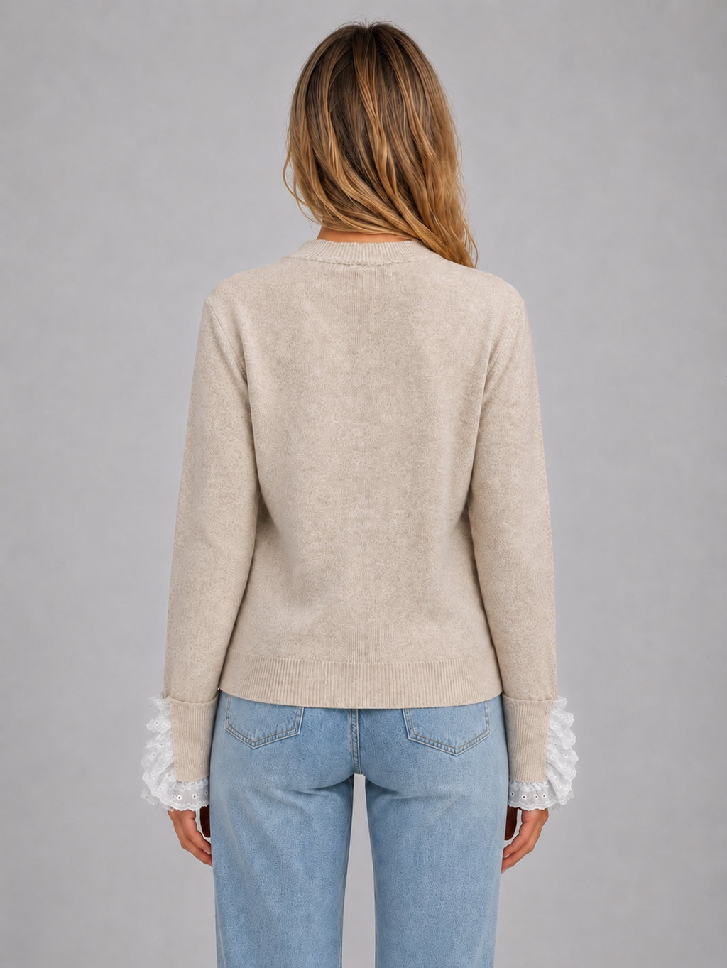 Woman wearing beige crew neck knitted jumper with lace trim sleeves and light blue jeans, back view