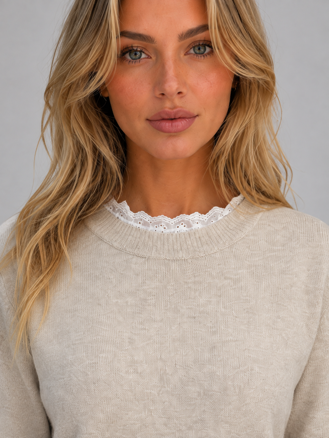 Woman wearing beige crew neck long sleeve knitted jumper with white lace trim detail at neckline