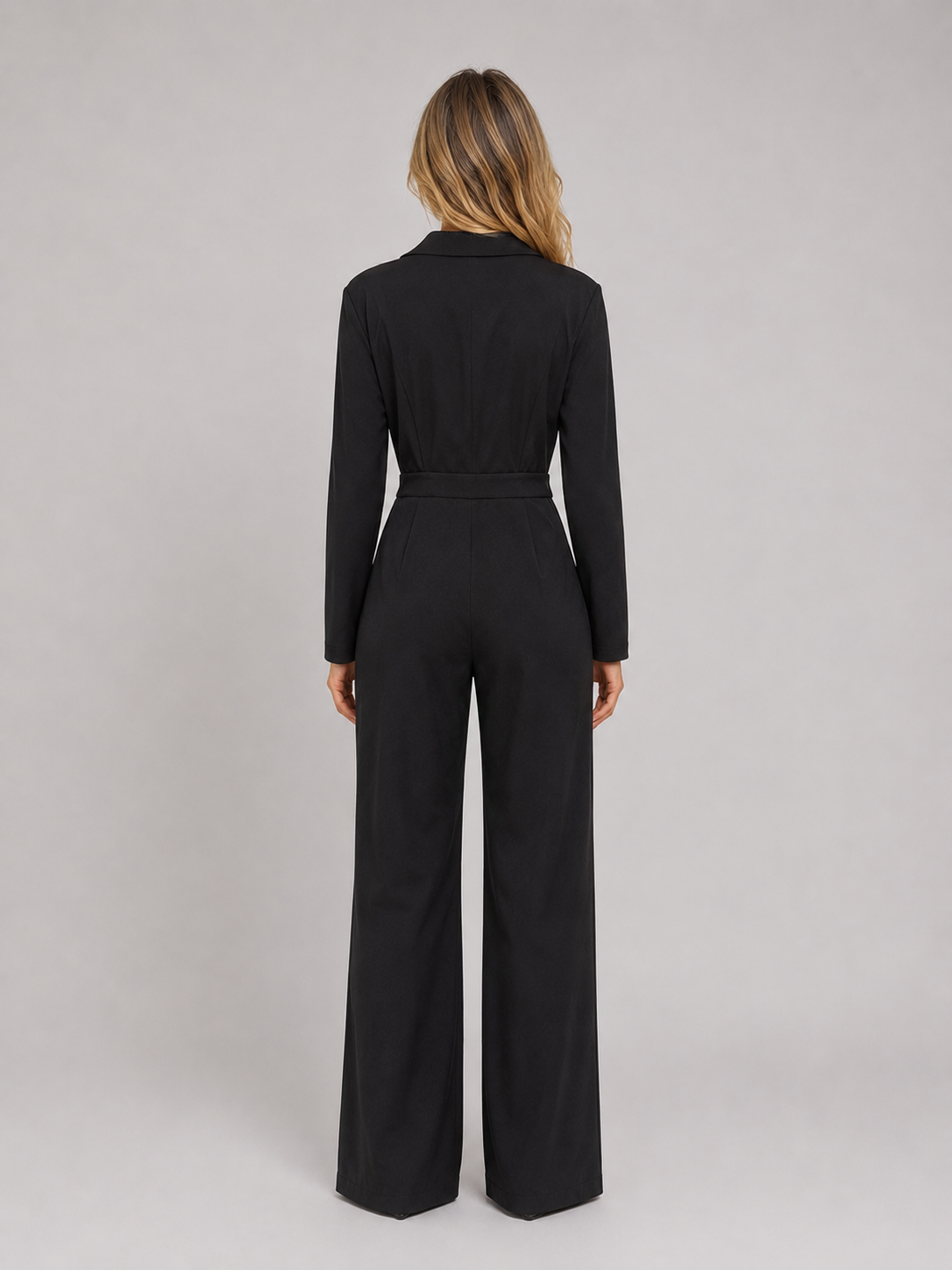 Woman wearing black belted tailored wrap front wide leg jumpsuit, back view