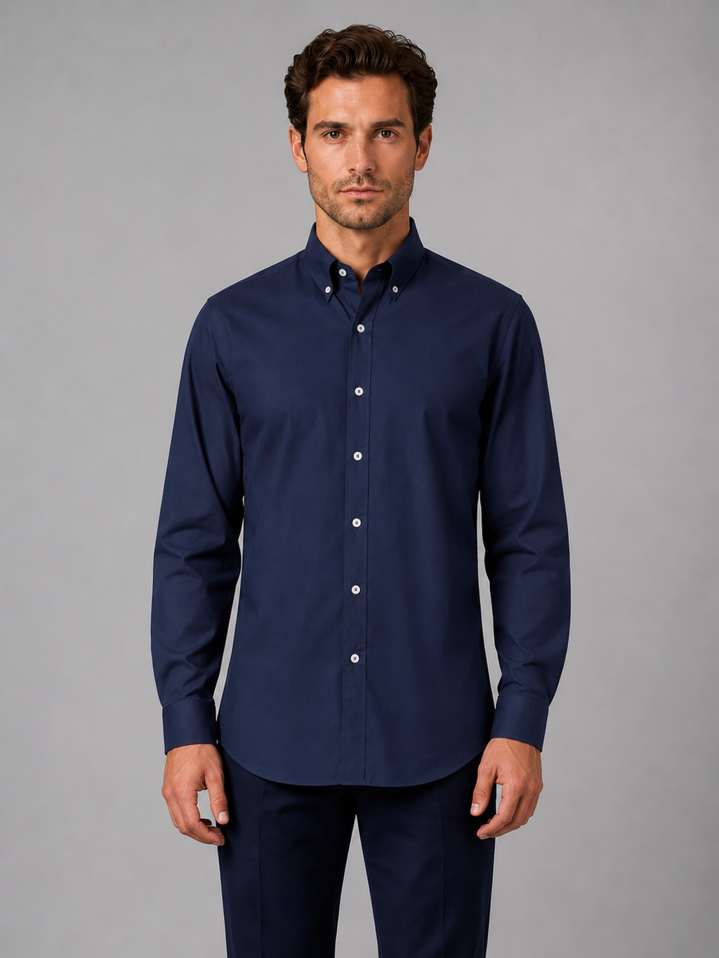 Man wearing navy blue button down collar long sleeve dress shirt with white buttons, paired with dark navy trousers