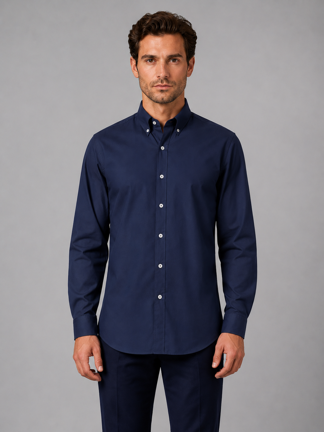 Man wearing navy blue button down collar long sleeve dress shirt with white buttons, paired with dark navy trousers