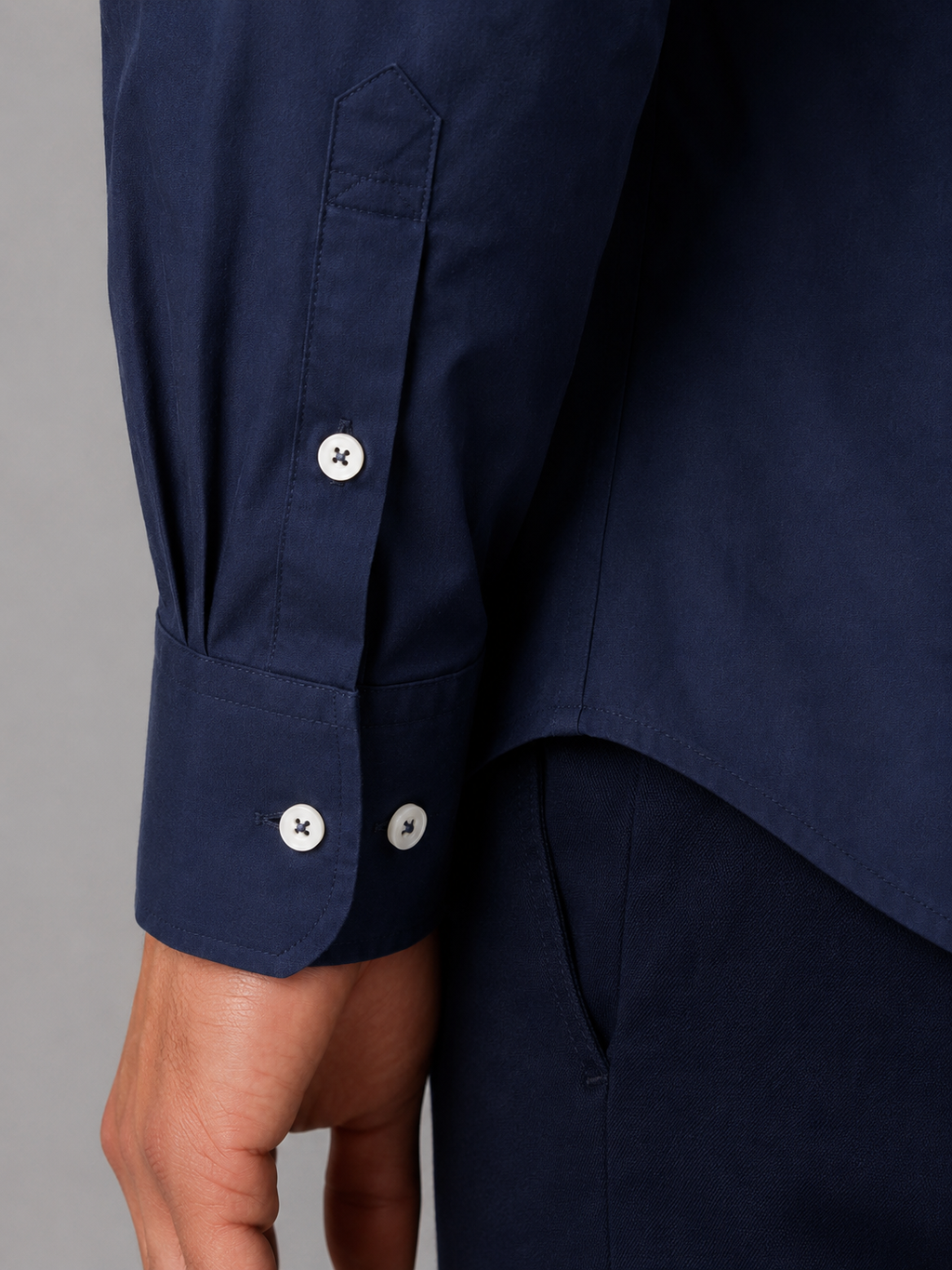 Navy blue button-down collar long sleeve shirt with white buttons and adjustable cuff detail on wrist