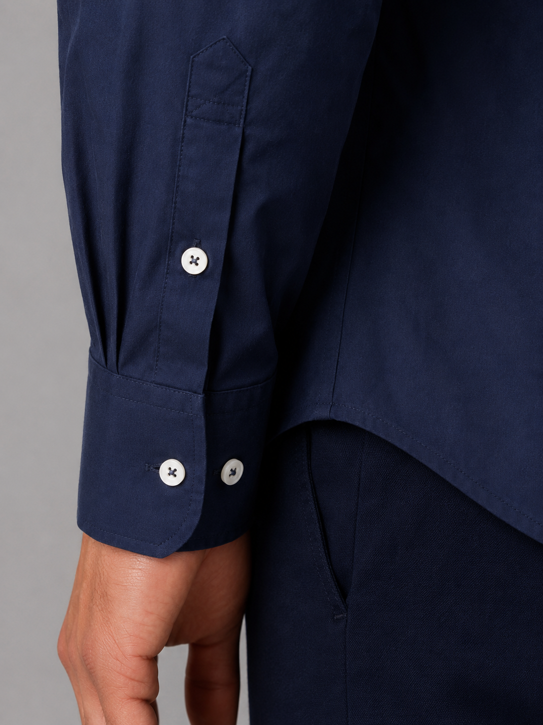Navy blue button-down collar long sleeve shirt with white buttons and adjustable cuff detail on wrist