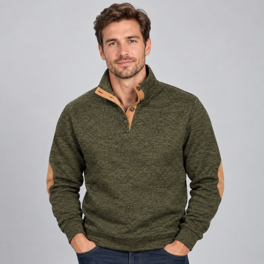 Man wearing olive green quarter button stand collar jumper with tan contrast trim and elbow patches, hands in pockets