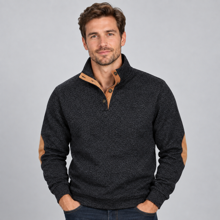 Man wearing charcoal grey quarter button stand collar jumper with tan suede elbow patches and navy jeans