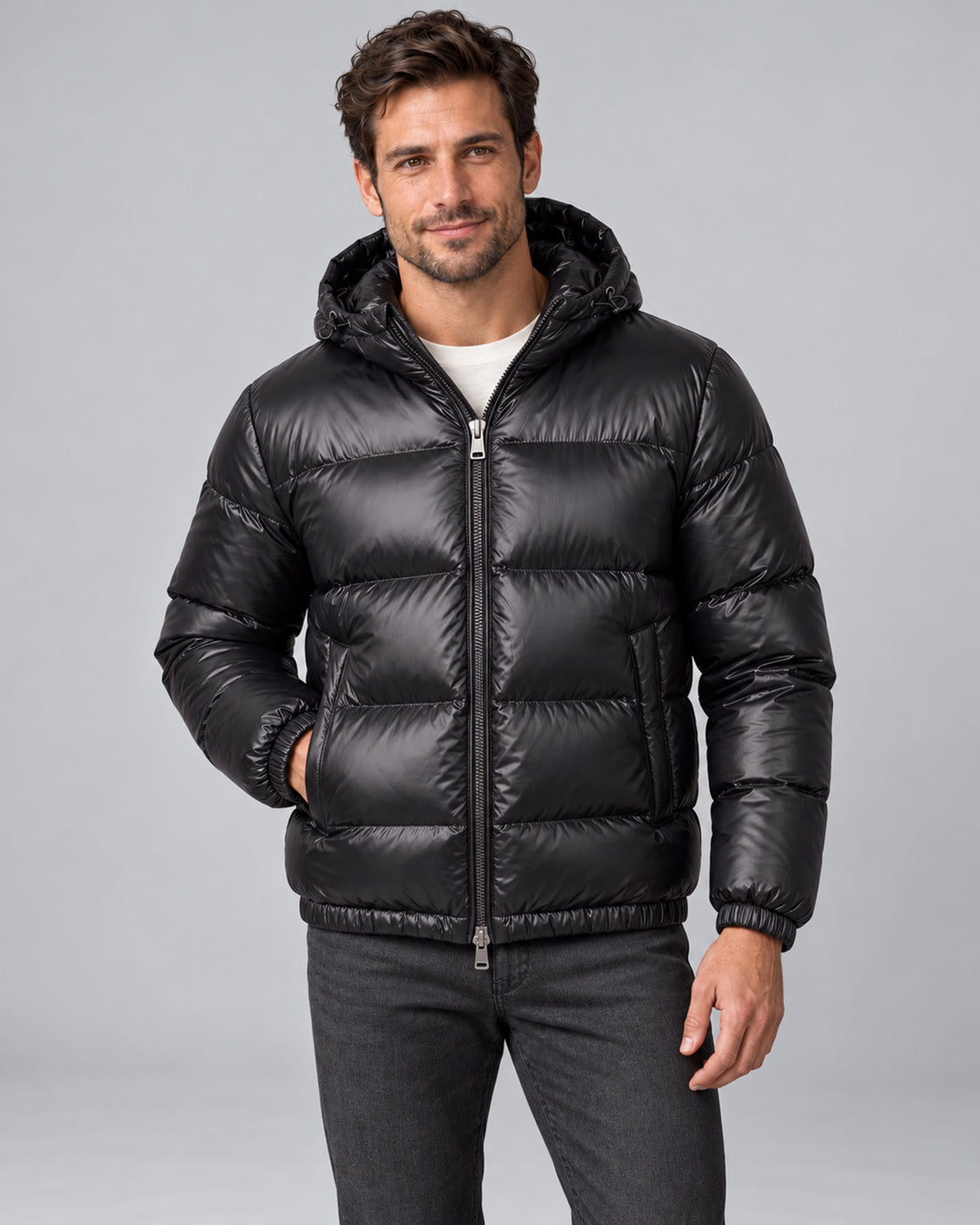 Men's black hooded quilted puffer jacket front with one hand in jacket pocket