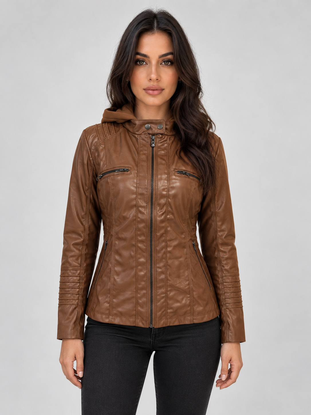 Woman wearing a brown fitted leather hooded biker jacket with zip front and chest pockets, paired with black pants