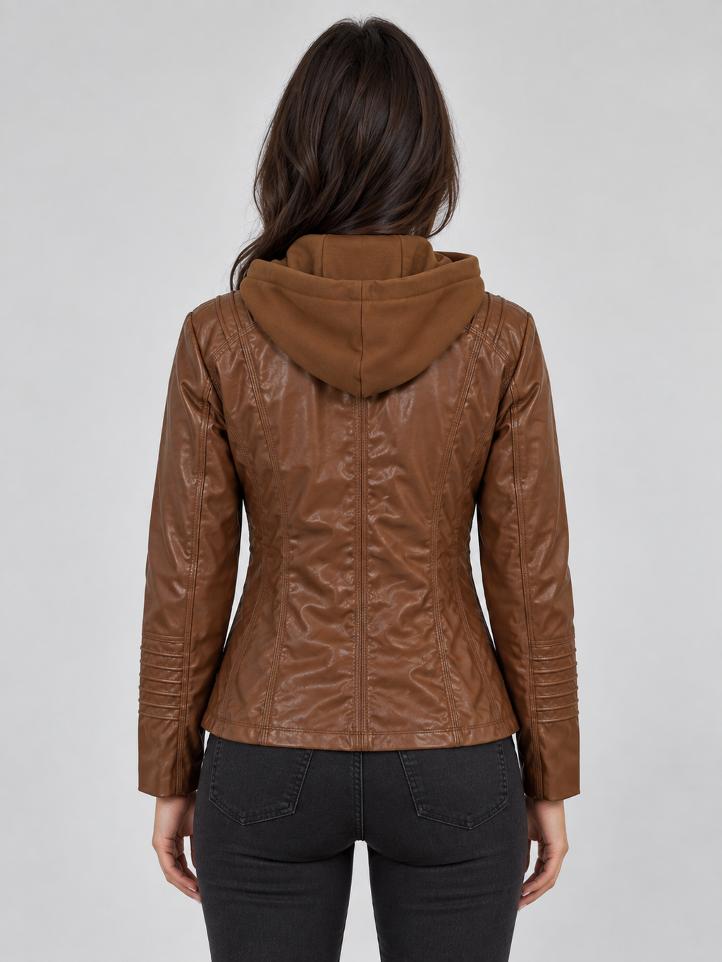 Woman wearing brown fitted hooded leather biker jacket with dark jeans, back view