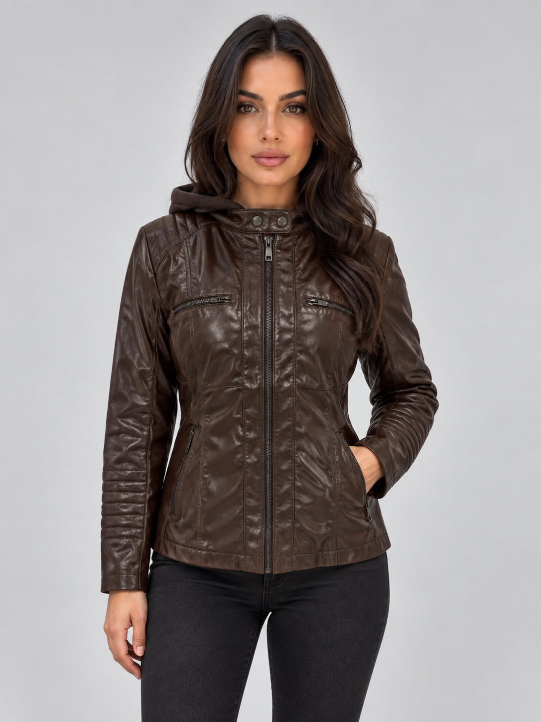 Woman wearing brown fitted hooded leather biker jacket with front zip and chest pockets, paired with black pants