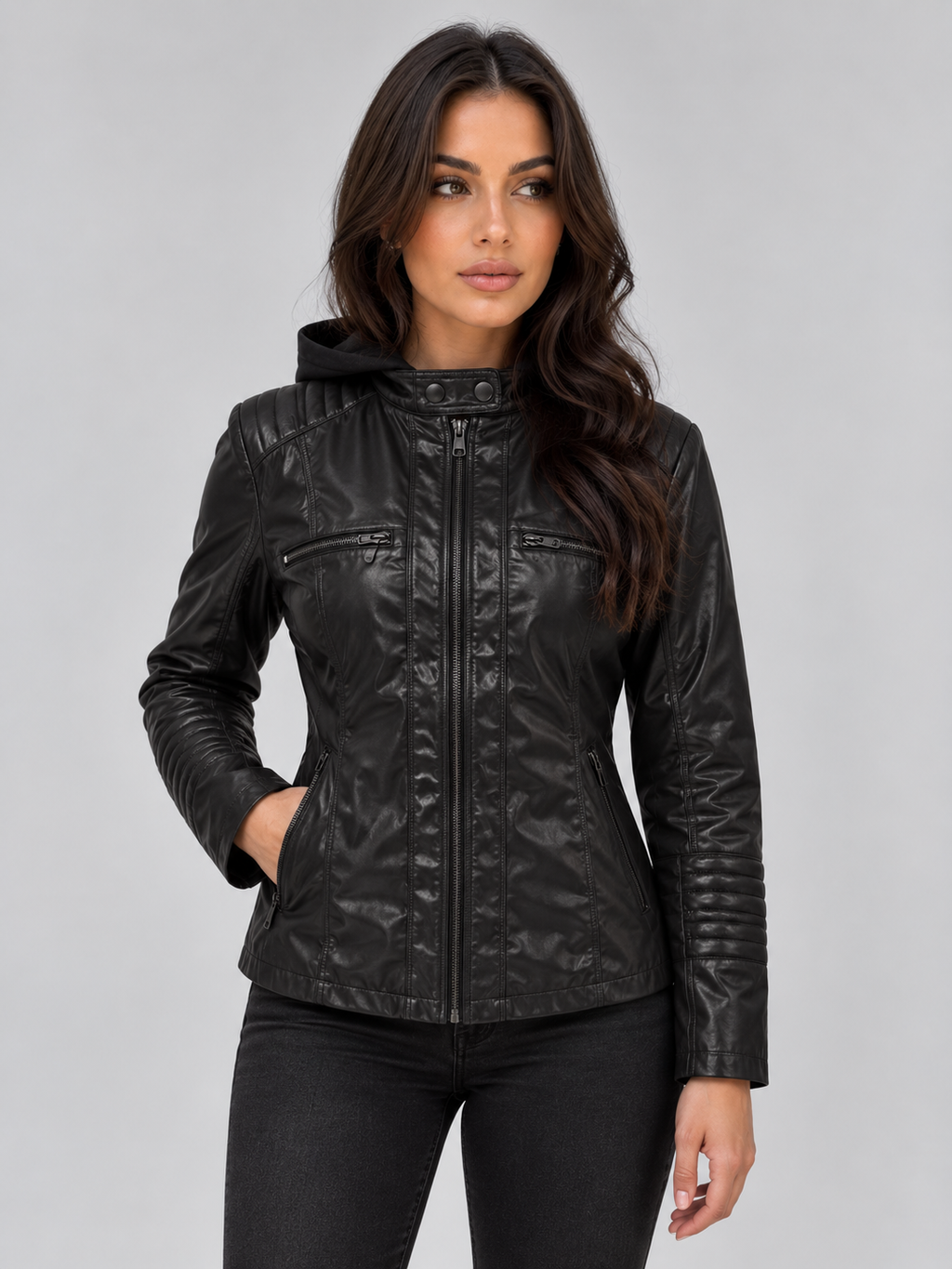 Woman wearing black fitted hooded leather biker jacket with front zip and chest pockets over dark jeans