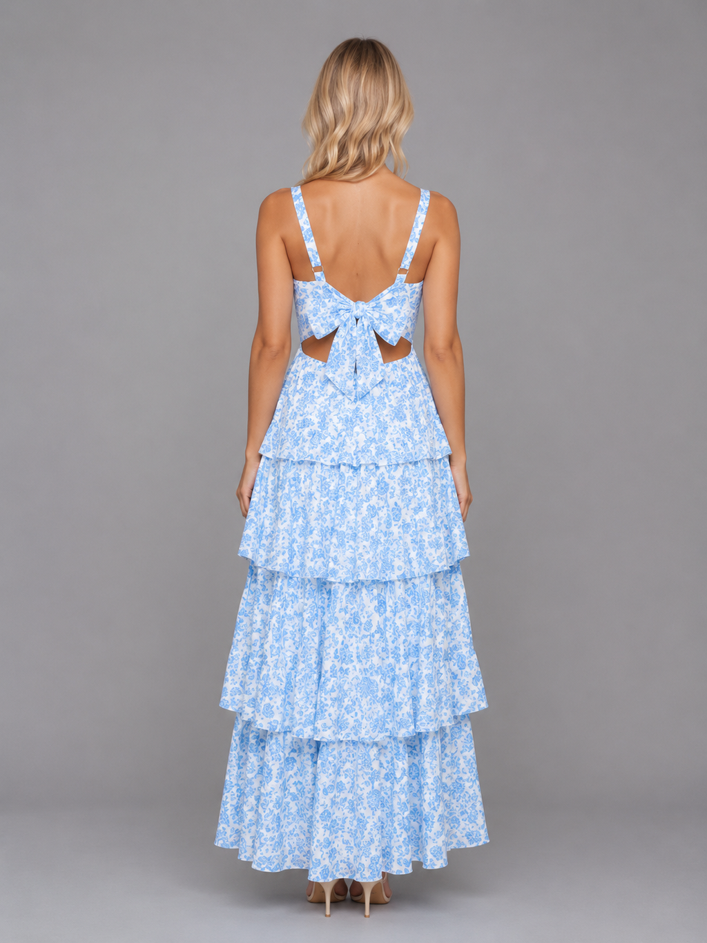 Woman wearing light blue floral tiered maxi dress with bow back detail and strappy shoulders, shown from behind