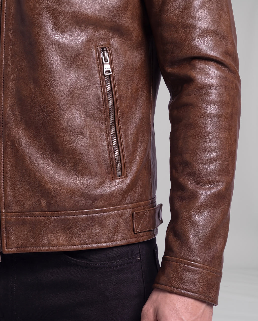 Close-up of the Garrett jacket in Cigar Brown: vertical hip zip pocket, waistband snap tab and sleeve cuff
