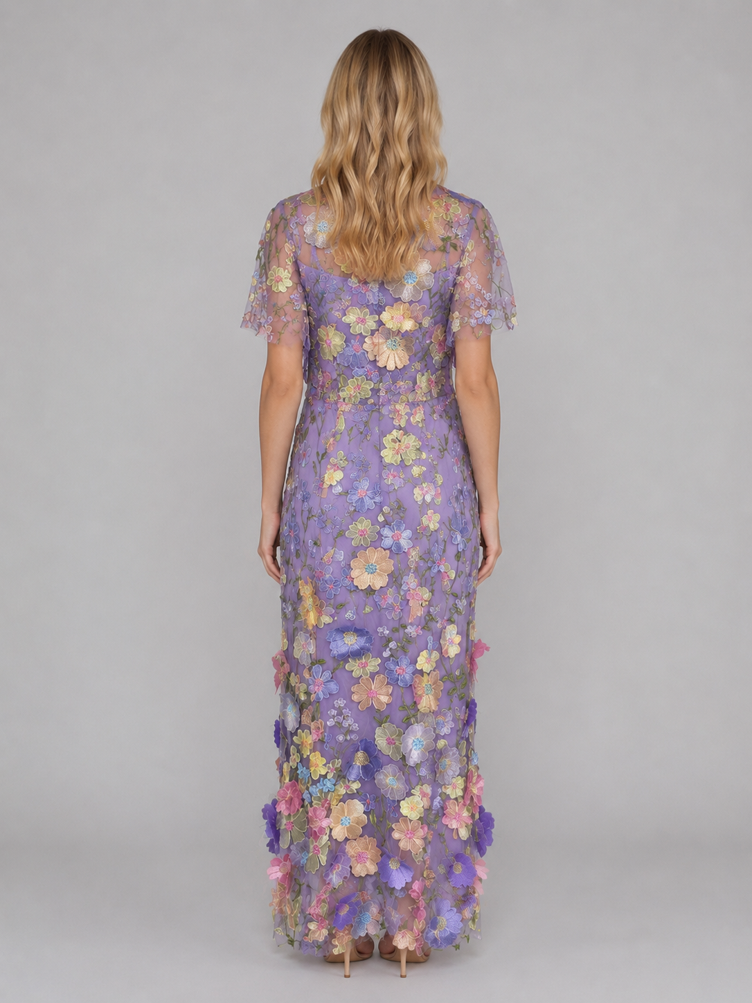 Woman wearing purple 3D floral embroidered tulle maxi gown with colorful flowers and short sleeves, shown from back view