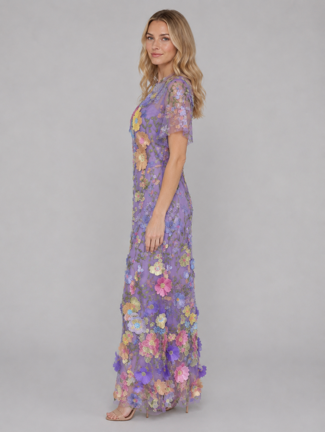 Woman wearing purple 3D floral embroidered tulle maxi gown with multicolor flowers and short sleeves