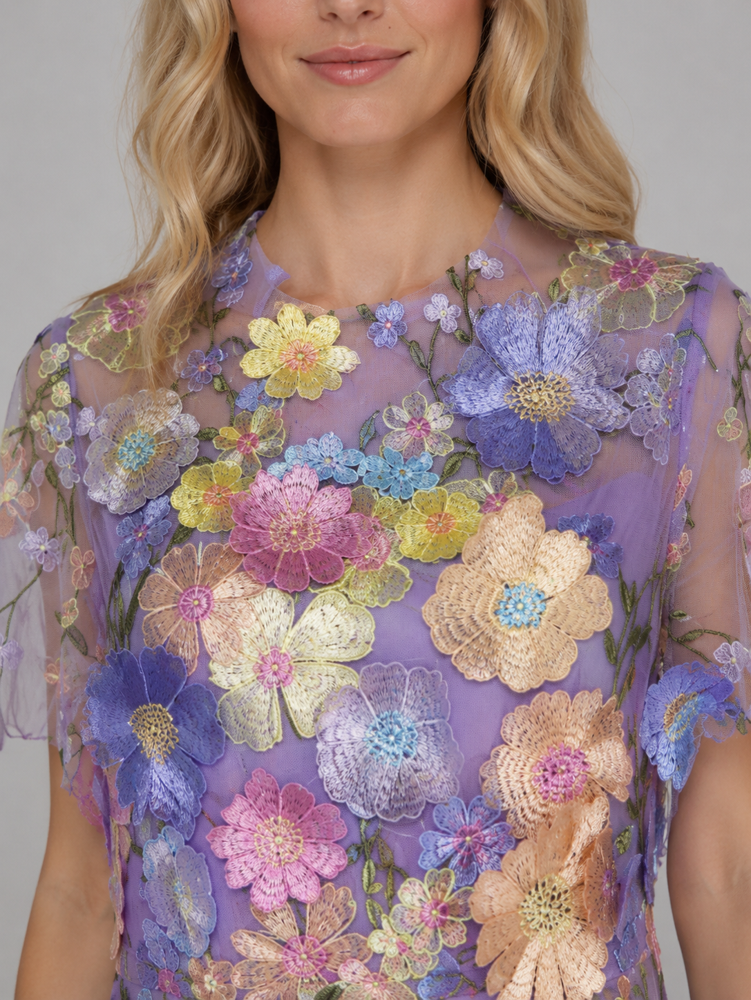 Woman wearing lavender tulle maxi dress with 3D embroidered flowers in purple, yellow, pink, blue and cream colors